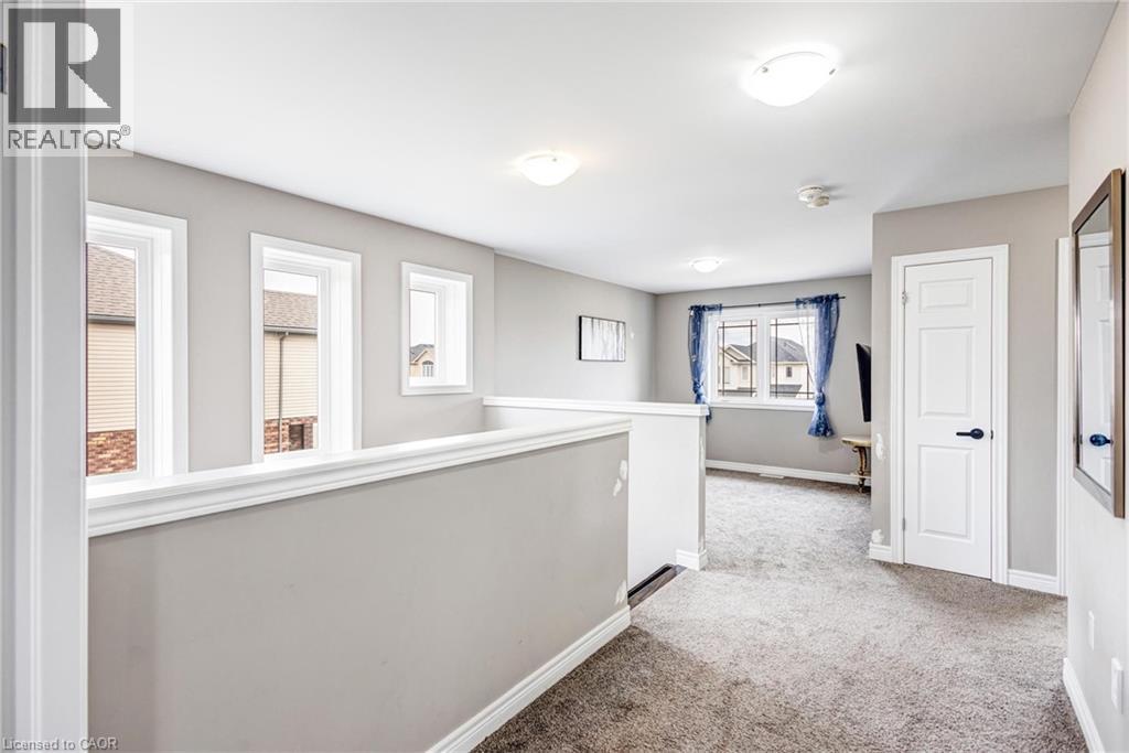 Upper-level landing featuring a white railing and neutral gray walls - 417 Rivertrail Avenue, Kitchener, ON