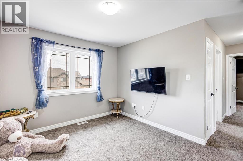 Carpeted room featuring a white-framed window, light gray walls, white baseboards, and two white panel doors - 417 Rivertrail Avenue, Kitchener, ON