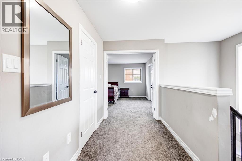 Carpeted hallway with light gray walls, white trim, and a white six-panel door - 417 Rivertrail Avenue, Kitchener, ON
