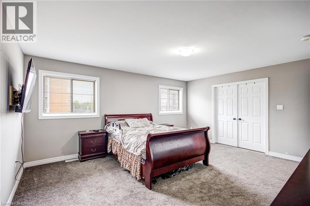 Spacious room featuring neutral paint, two windows with blinds, a ceiling-mounted light fixture, and double bi-fold doors - 417 Rivertrail Avenue, Kitchener, ON