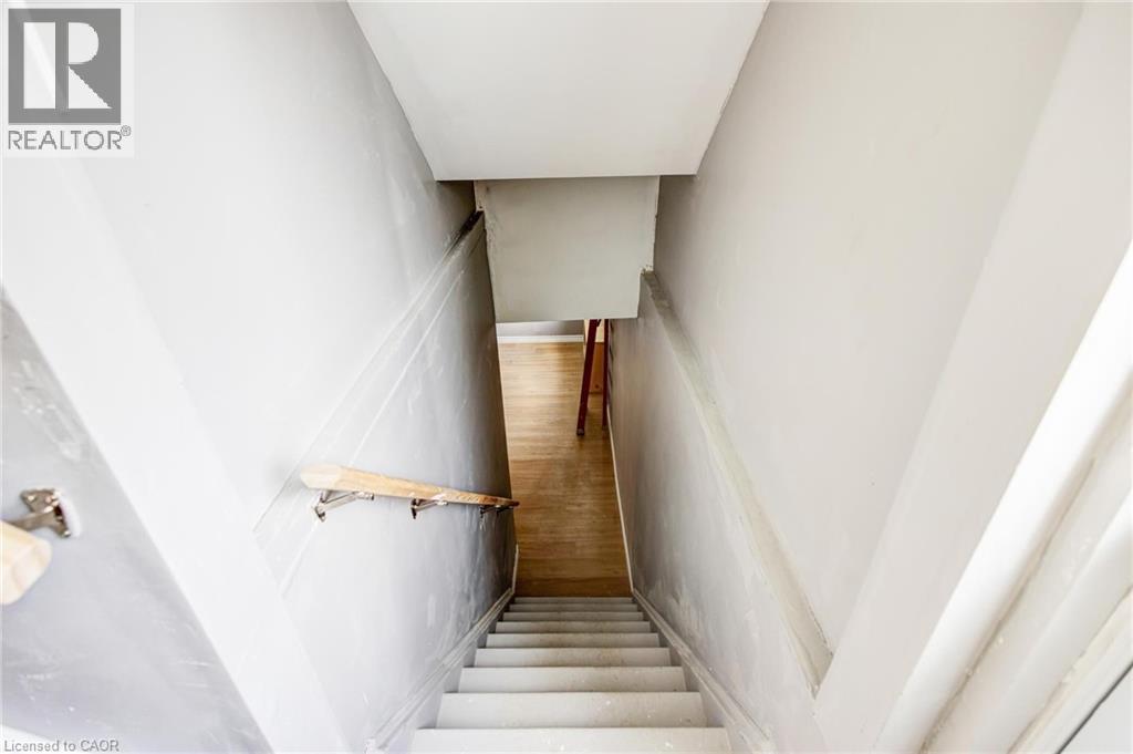 Stairwell with light grey walls, white trim, and a natural wood handrail - 417 Rivertrail Avenue, Kitchener, ON