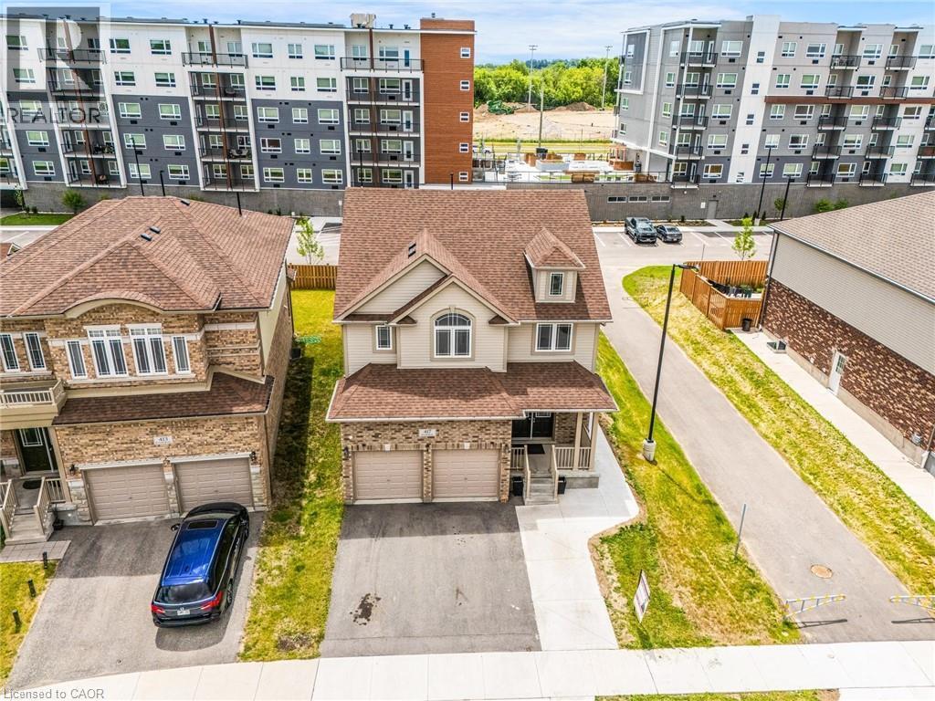 Two-story residence featuring a dual-car garage, front porch, dormer window, and light-toned siding with brick accents - 417 Rivertrail Avenue, Kitchener, ON
