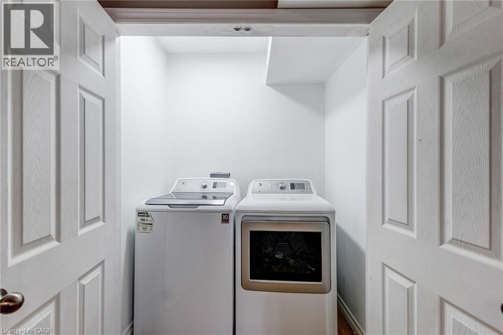 Dedicated laundry alcove with white walls, wood-finish flooring, and bi-fold panel doors - 417 Rivertrail Avenue, Kitchener, ON