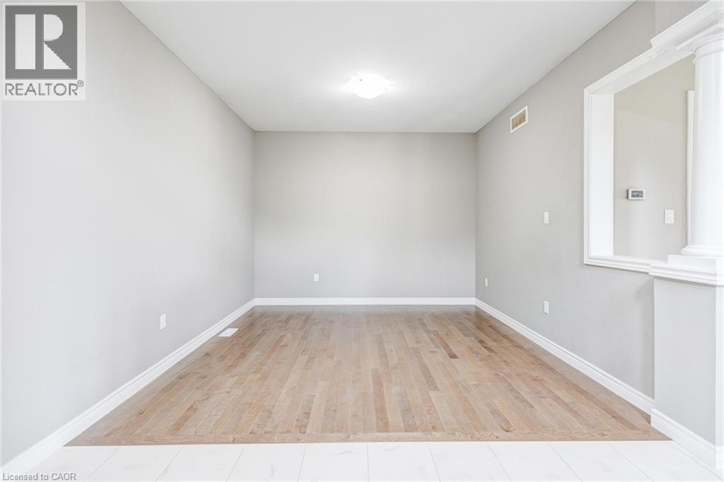 Bright interior room featuring wood-finish flooring, light grey painted walls, white baseboards, and a ceiling-mounted light fixture - 417 Rivertrail Avenue, Kitchener, ON