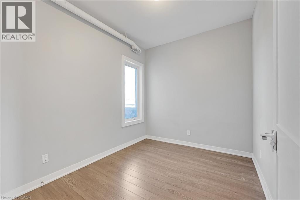 Room featuring wood-finish flooring, light grey walls, and a white-framed window - 657 Barton Street E Unit# 302, Hamilton, ON