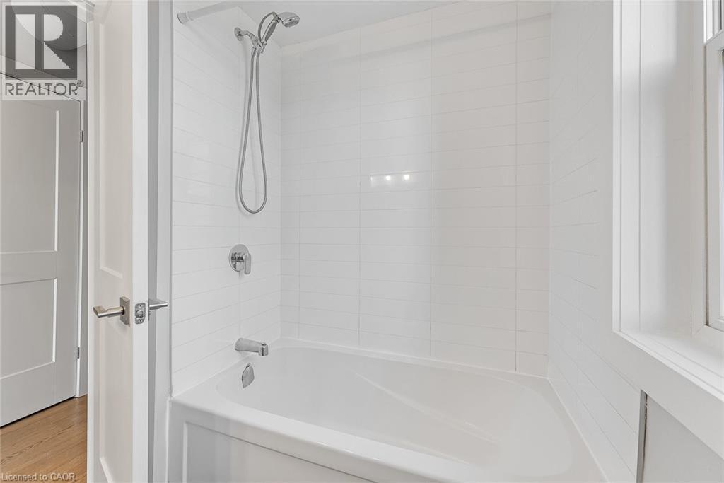 Bathtub and shower combination featuring white subway tile surround, polished chrome fixtures, and a handheld showerhead - 657 Barton Street E Unit# 302, Hamilton, ON