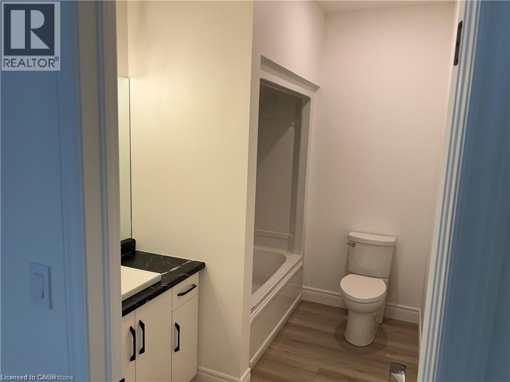 Bathroom with vanity, wood finished floors, toilet, baseboards, and shower / tub combination - 207 Arden Crescent Unit# Upper Level, Mitchell, ON