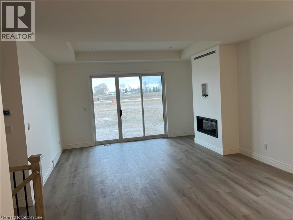 Unfurnished living room with a tray ceiling, wood finished floors, a glass covered fireplace, and baseboards - 207 Arden Crescent Unit# Upper Level, Mitchell, ON