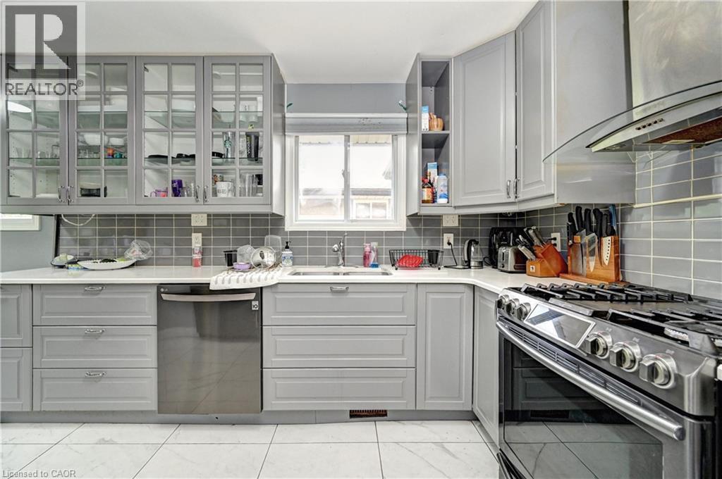 Contemporary kitchen featuring light gray cabinetry, quartz-finish countertops, and a subway tile backsplash - 525 Fallingbrook Drive, Waterloo, ON