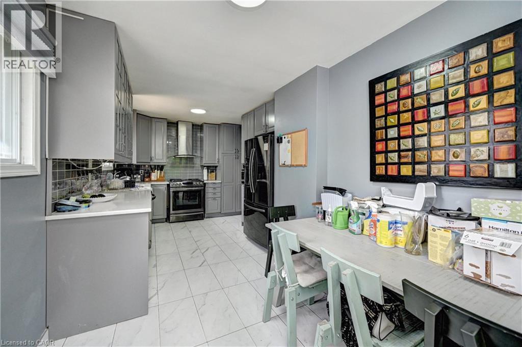 Modern kitchen featuring grey cabinetry, white countertops, tile flooring, stainless steel range, and a coordinating range hood - 525 Fallingbrook Drive, Waterloo, ON
