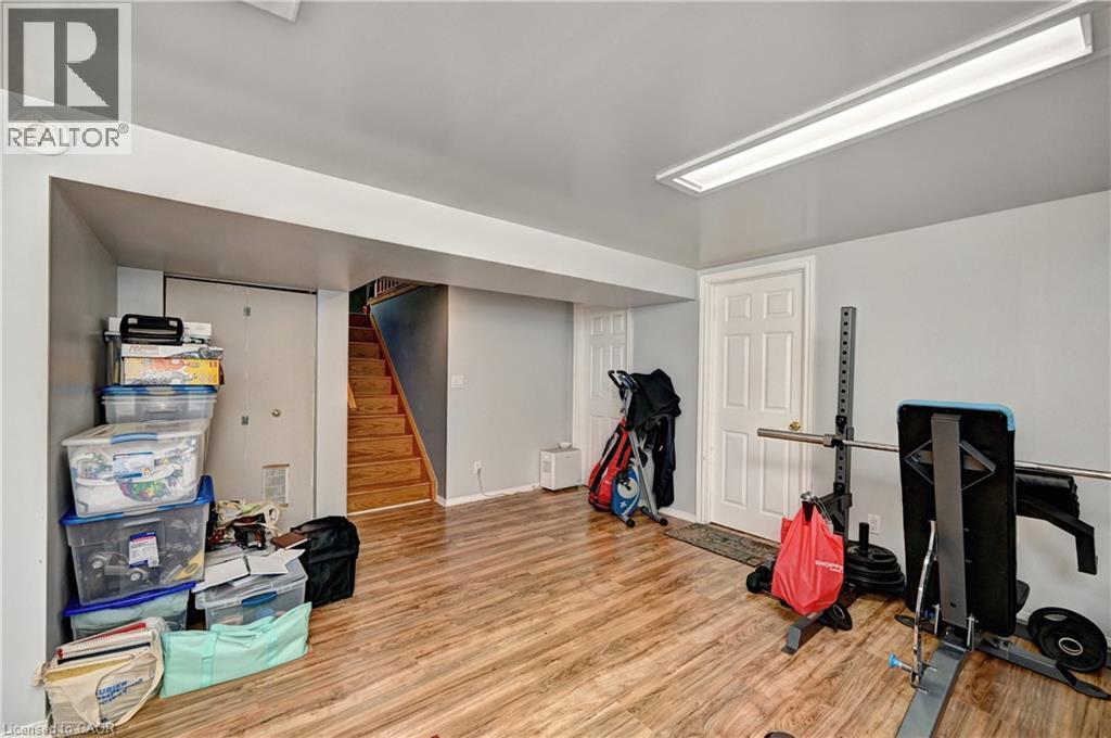 Finished lower level featuring wood-finish flooring, light grey walls, white trim, and a white paneled door - 525 Fallingbrook Drive, Waterloo, ON