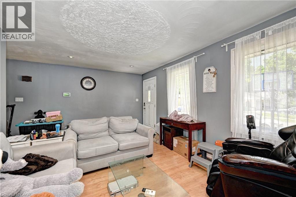 Living space featuring wood-finish flooring, two large windows, a white entry door, recessed lighting, and a textured ceiling - 525 Fallingbrook Drive, Waterloo, ON