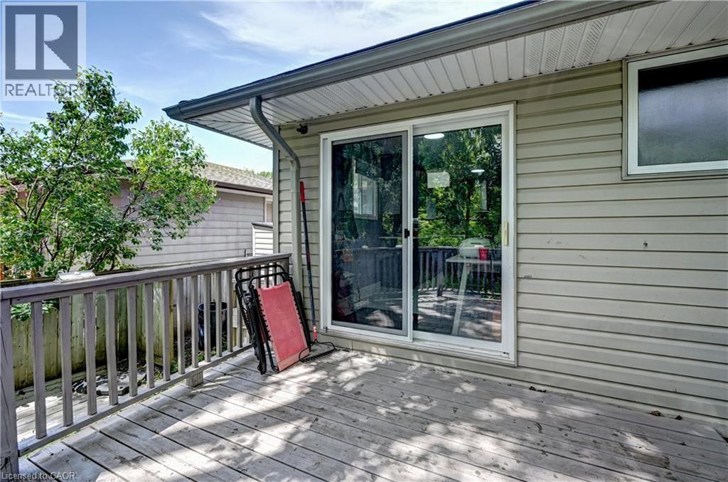 Outdoor wood deck with a wooden railing, featuring a large sliding glass door and a horizontal window - 525 Fallingbrook Drive, Waterloo, ON