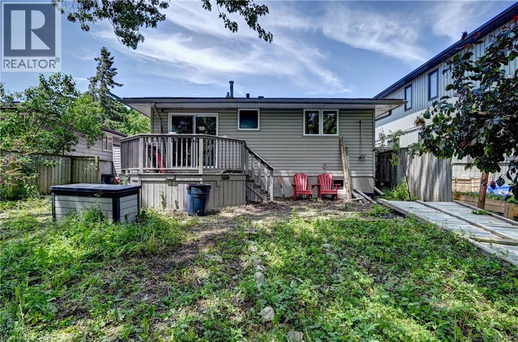 Rear exterior featuring a wooden deck with railing, sliding glass doors, and two windows - 525 Fallingbrook Drive, Waterloo, ON