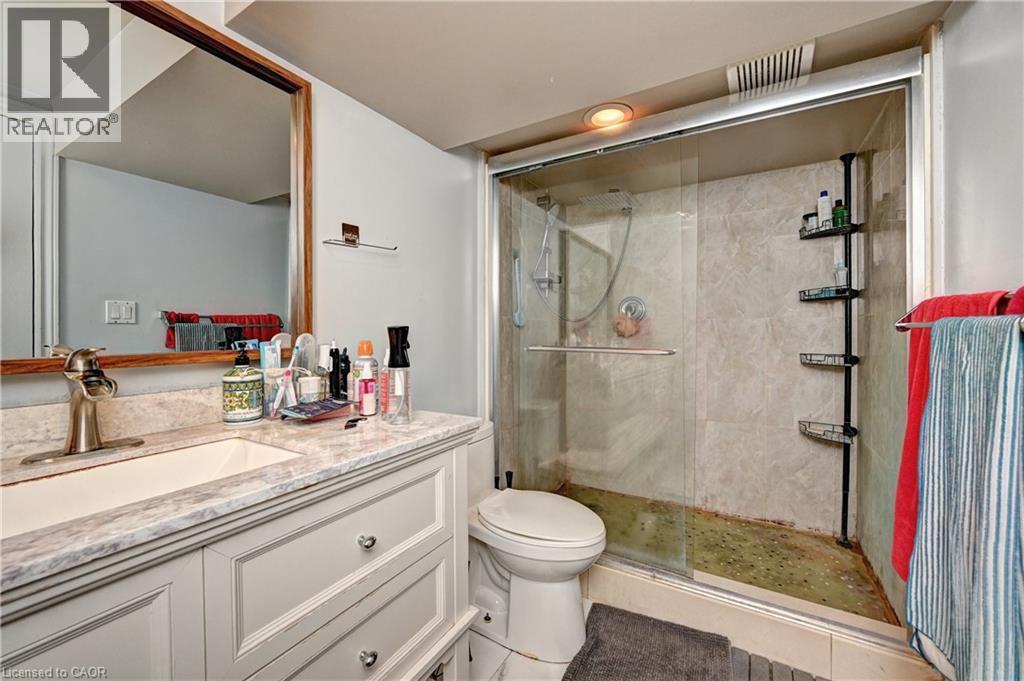 Bathroom featuring a light-colored vanity with a built-in sink, a framed mirror, and a glass-enclosed shower with tiled walls - 525 Fallingbrook Drive, Waterloo, ON