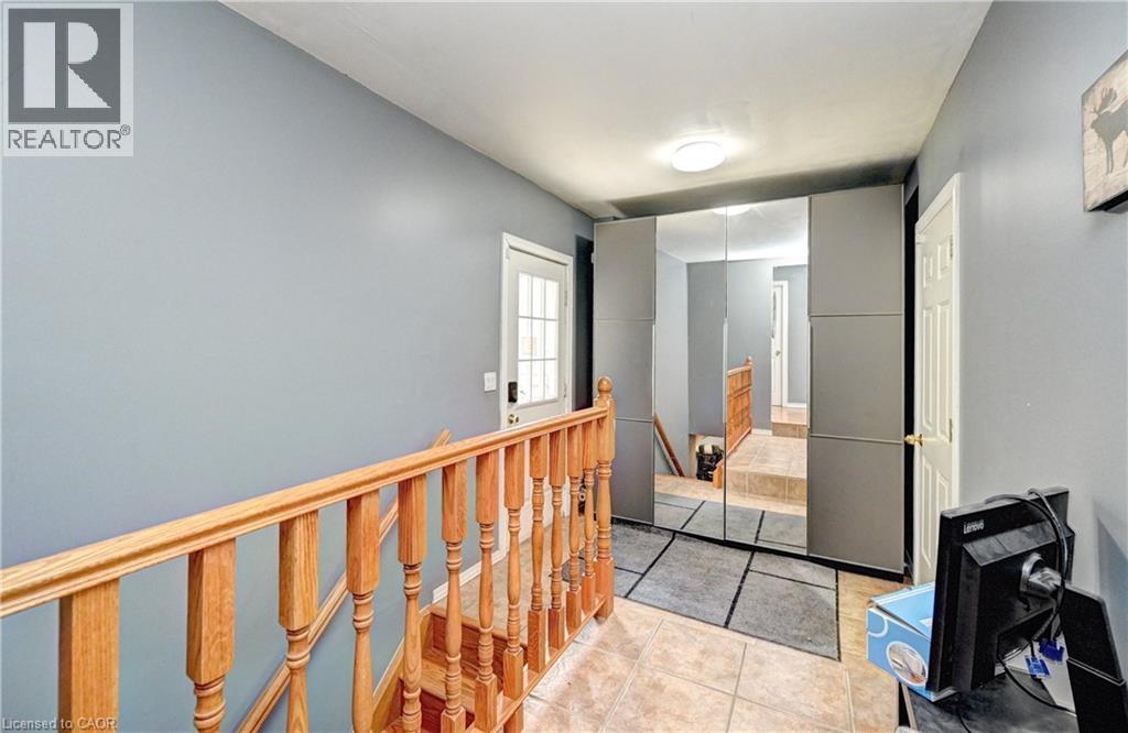 Upper floor landing with wood railing, light blue walls, and ceramic tile flooring - 525 Fallingbrook Drive, Waterloo, ON