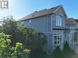 Stone and siding exterior featuring a prominent bay window, upper arched window, and balcony with white railings -