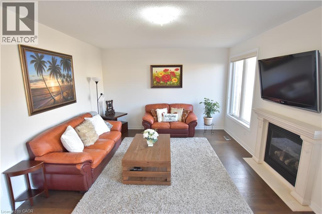 Living room featuring dark wood finished floors and a fireplace with flush hearth - 512 Terrington Crescent, Kitchener, ON