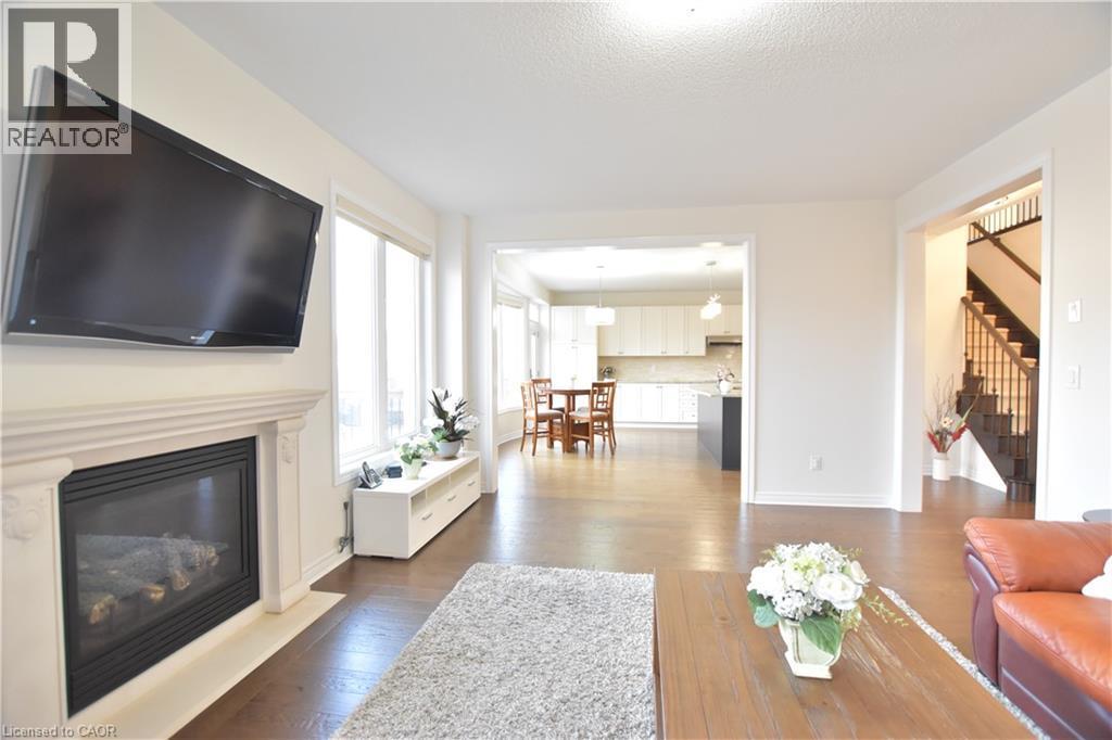 Living area featuring a glass covered fireplace and dark wood-style floors - 512 Terrington Crescent, Kitchener, ON
