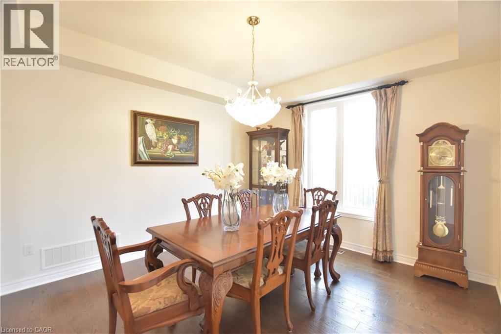 Dining area featuring dark wood-style flooring, a chandelier, and a tray ceiling - 512 Terrington Crescent, Kitchener, ON