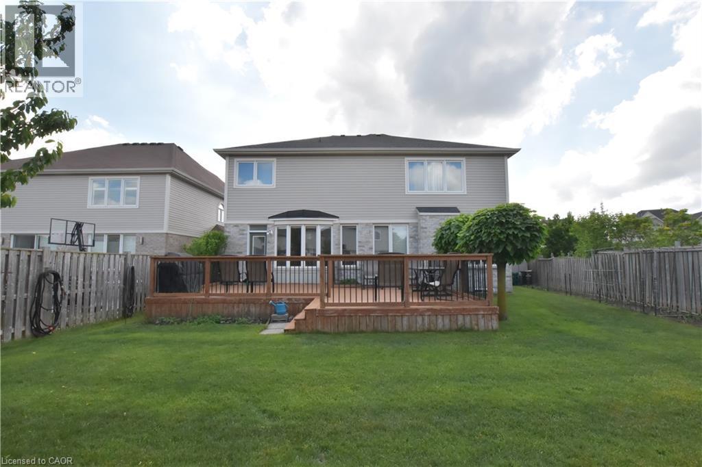 Expansive backyard featuring a large wooden deck with dark railings, a manicured lawn, and perimeter fencing - 512 Terrington Crescent, Kitchener, ON