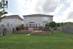 Expansive backyard featuring a large wooden deck with dark railings, a manicured lawn, and perimeter fencing -