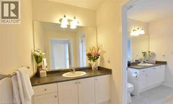 Dual bathroom vanities each featuring an integrated sink, dark countertops, and white cabinetry -