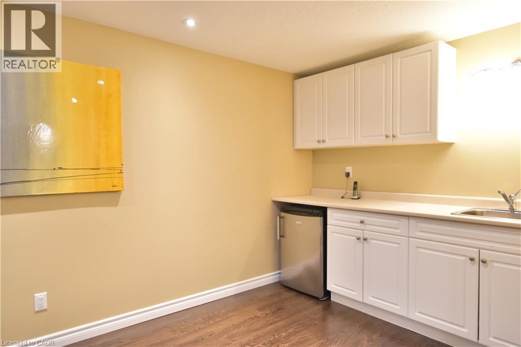 Kitchen with white cabinetry, light countertops, dark wood-style floors, recessed lighting, and stainless steel dishwasher - 512 Terrington Crescent, Kitchener, ON