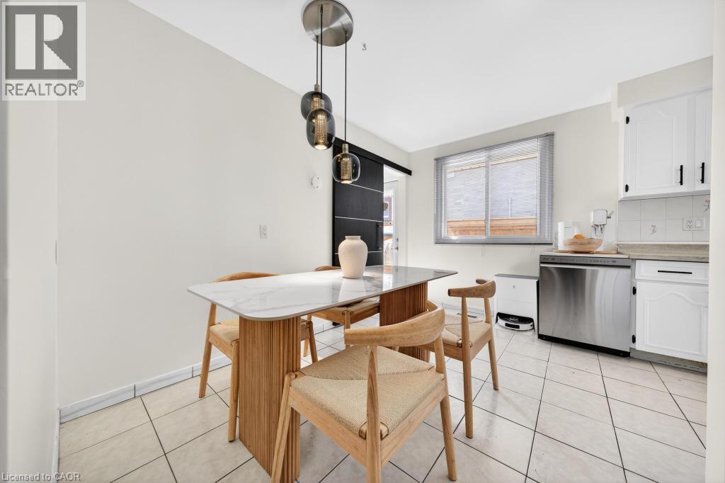 Dining area featuring a contemporary pendant light fixture, white tile flooring, and a barn door - 19 Glen Forest Drive, Hamilton, ON