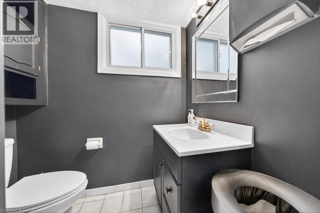 Bathroom featuring a white window, built-in medicine cabinet, dark vanity with white countertop, and tile flooring - 19 Glen Forest Drive, Hamilton, ON