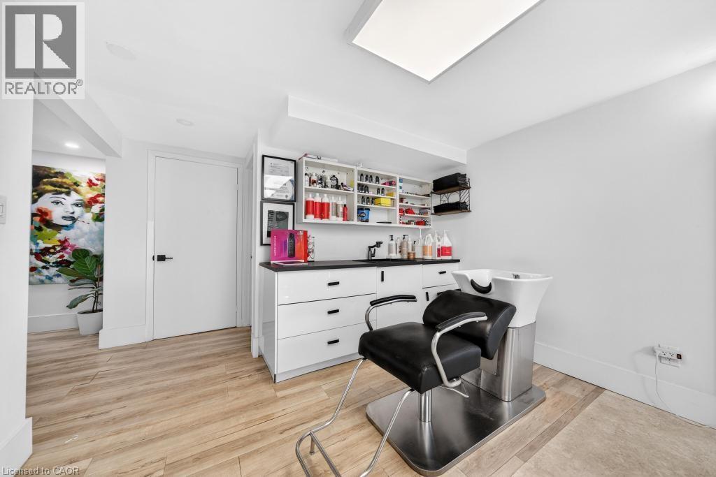 Bright interior space featuring wood-finish flooring, white walls, and a recessed ceiling light panel - 19 Glen Forest Drive, Hamilton, ON