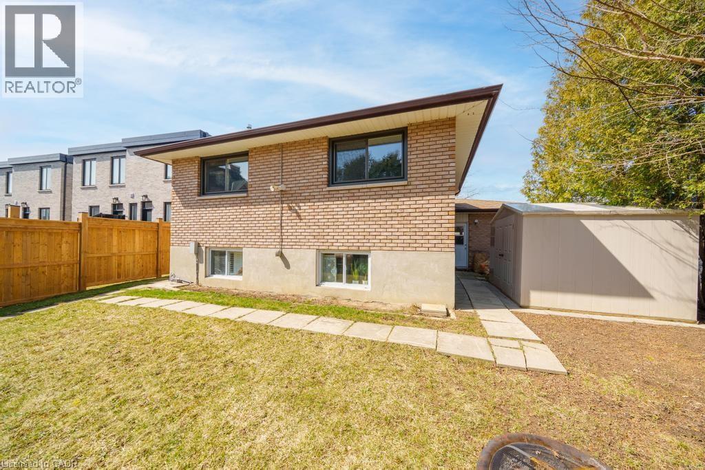 Rear exterior featuring brick siding, a brown roofline, and multiple windows - 19 Glen Forest Drive, Hamilton, ON