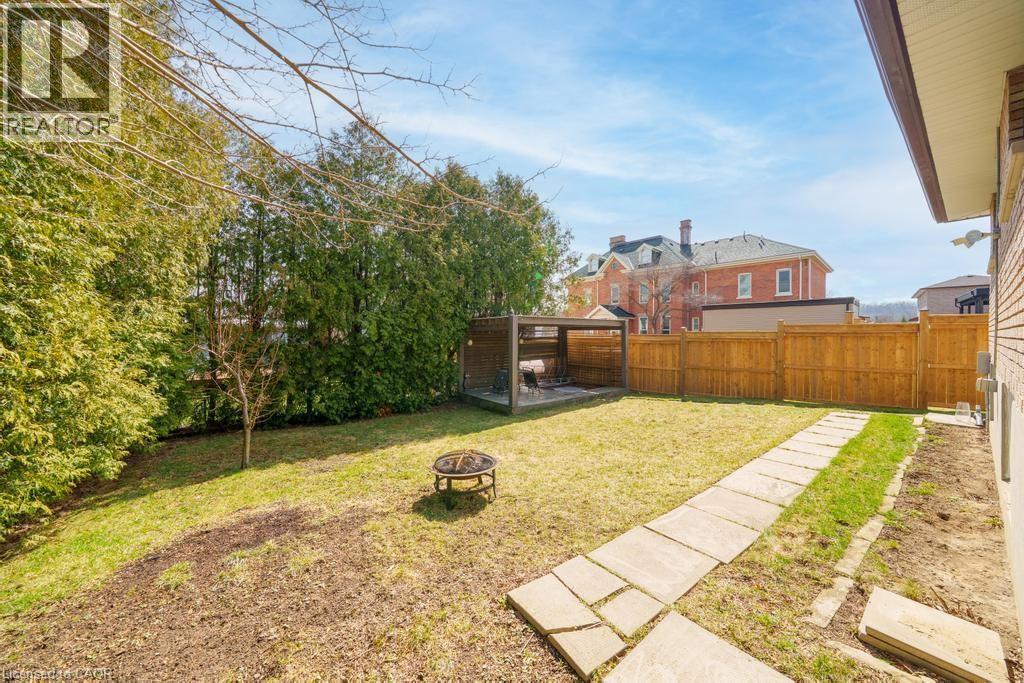 Expansive backyard featuring a stone pathway, wood privacy fencing, and mature perimeter trees - 19 Glen Forest Drive, Hamilton, ON