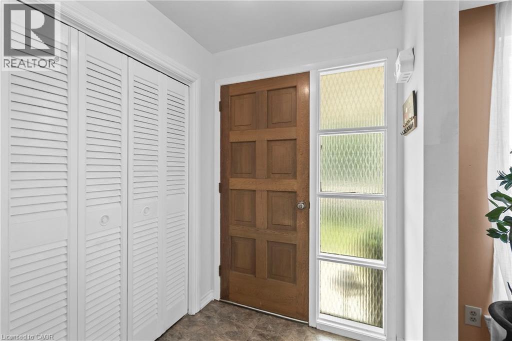 Entryway featuring a paneled wood door with a sidelight, white louvered bifold closet doors, and patterned floor tile - 1083 Melton Drive, Mississauga, ON