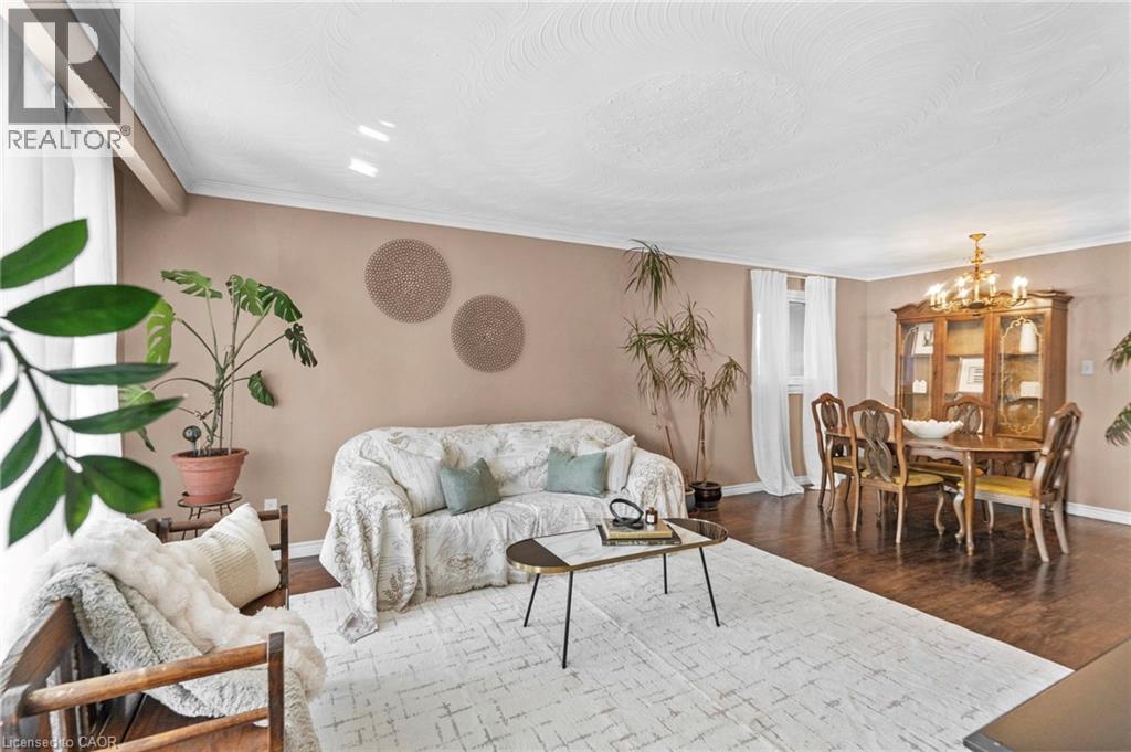 Combined living and dining area featuring wood-finish flooring, neutral wall tones, and crown molding - 1083 Melton Drive, Mississauga, ON