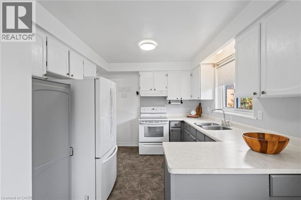 Bright kitchen featuring white upper cabinetry, gray lower cabinetry, and light-toned countertops - 1083 Melton Drive, Mississauga, ON