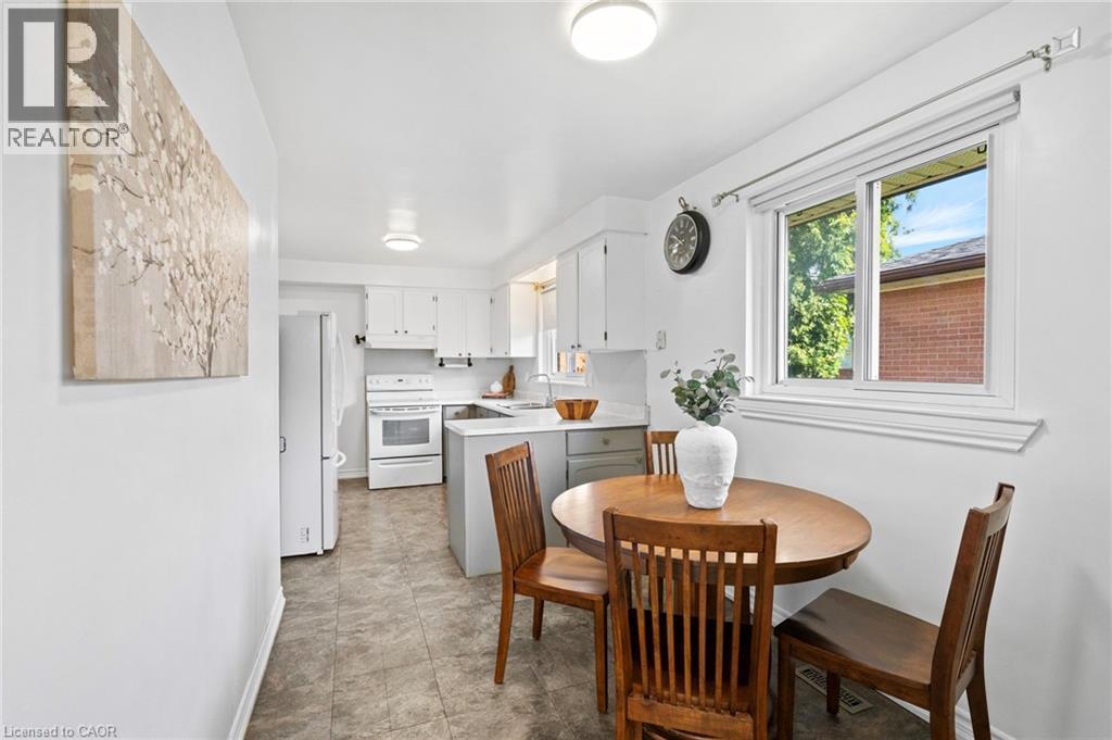 Bright kitchen featuring white cabinetry, white appliances, a window, and tile flooring - 1083 Melton Drive, Mississauga, ON
