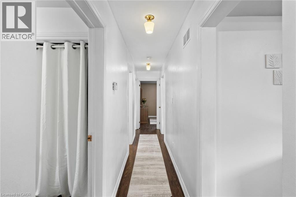 Hallway featuring dark wood-finish flooring, white walls, and flush-mount lighting fixtures - 1083 Melton Drive, Mississauga, ON