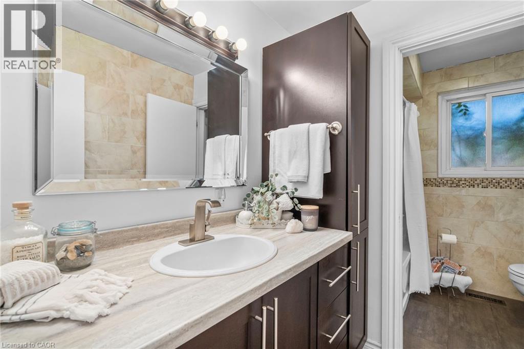 Bathroom vanity featuring an integrated sink, brushed nickel faucet, and a large framed mirror - 1083 Melton Drive, Mississauga, ON