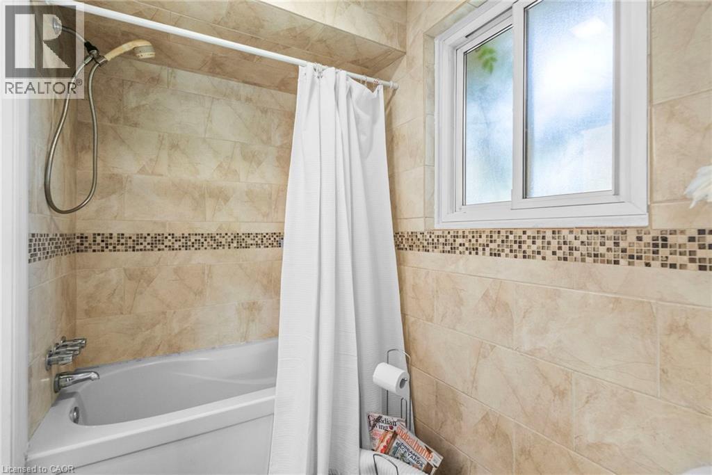 Bathtub-shower combination featuring a tiled surround with a decorative mosaic accent band - 1083 Melton Drive, Mississauga, ON