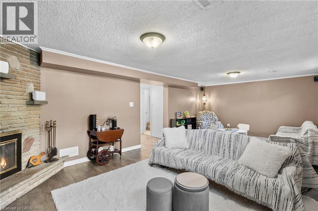 Spacious room featuring a stone fireplace with hearth, wood-finish flooring, and recessed lighting - 1083 Melton Drive, Mississauga, ON