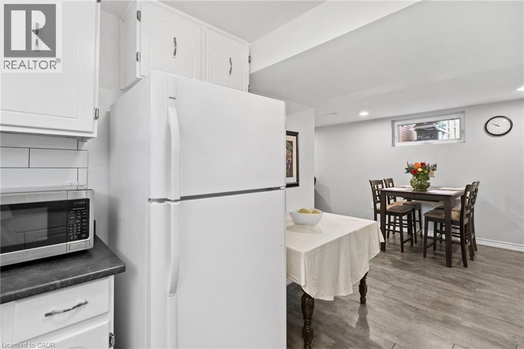 Basement Kitchen area featuring white cabinetry with brushed nickel hardware, a white refrigerator, and a dark countertop - 1083 Melton Drive, Mississauga, ON