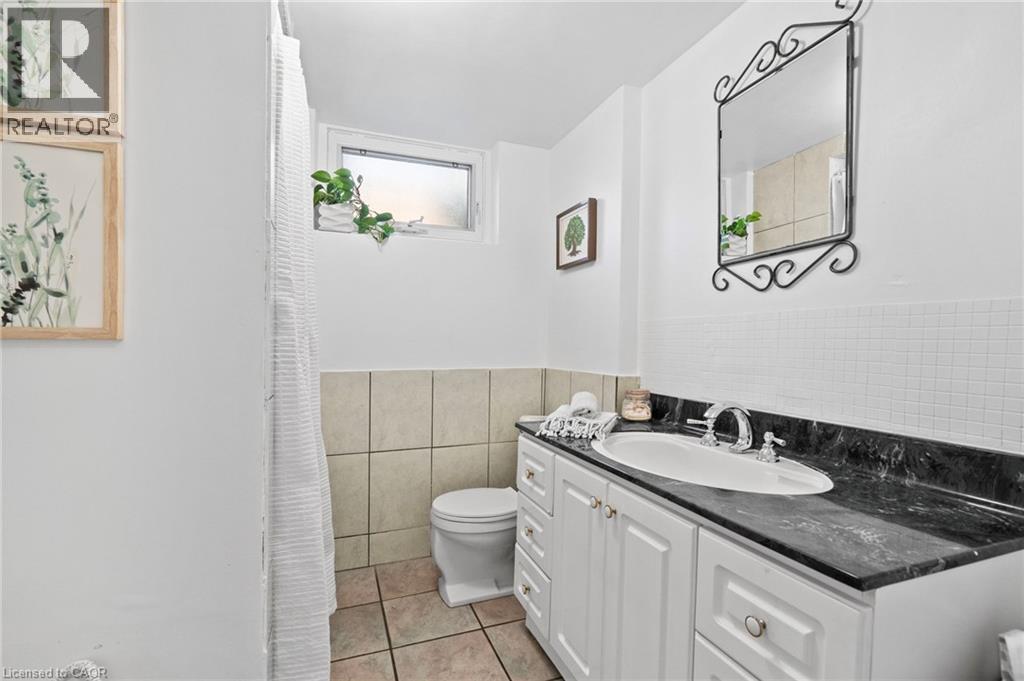 3-piece Basement bathroom featuring a white vanity with a dark countertop, an undermount sink, and a decorative wall mirror - 1083 Melton Drive, Mississauga, ON