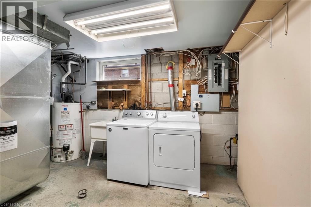 Utility space featuring a washer and dryer set, a utility sink, exposed block foundation, and overhead fluorescent lighting - 1083 Melton Drive, Mississauga, ON