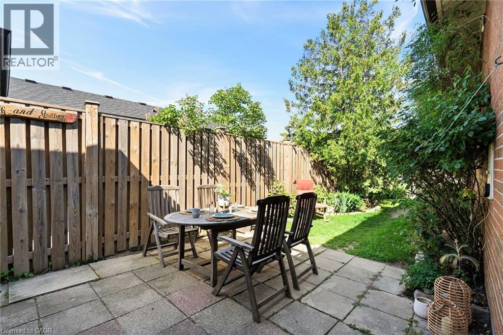 Private backyard featuring a stone paver patio, wood fencing, and established greenery - 1083 Melton Drive, Mississauga, ON