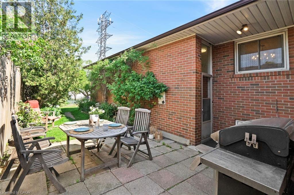 Rear patio featuring square pavers and a brick exterior, surrounded by mature plants and a fenced perimeter - 1083 Melton Drive, Mississauga, ON