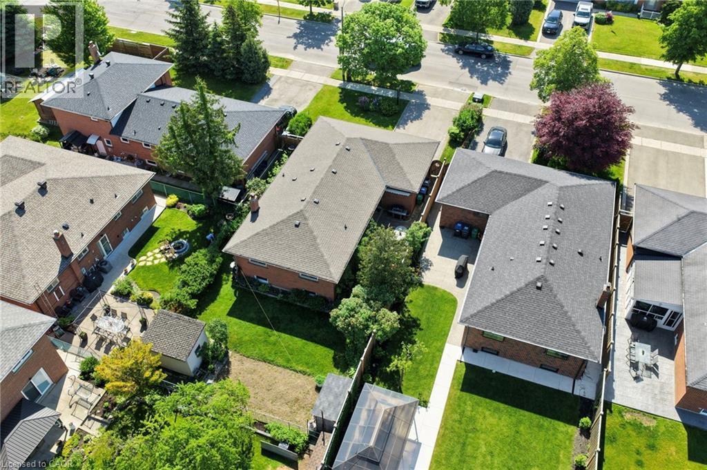 Aerial view showcasing an L-shaped brick residence with a dark shingle roof, a paved driveway, and established front and rear landscaping - 1083 Melton Drive, Mississauga, ON