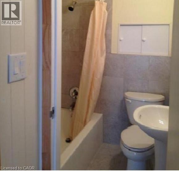 Bathroom featuring a pedestal sink, toilet, and a combination tub/shower with tiled surround - 269 Cannon Street E, Hamilton, ON