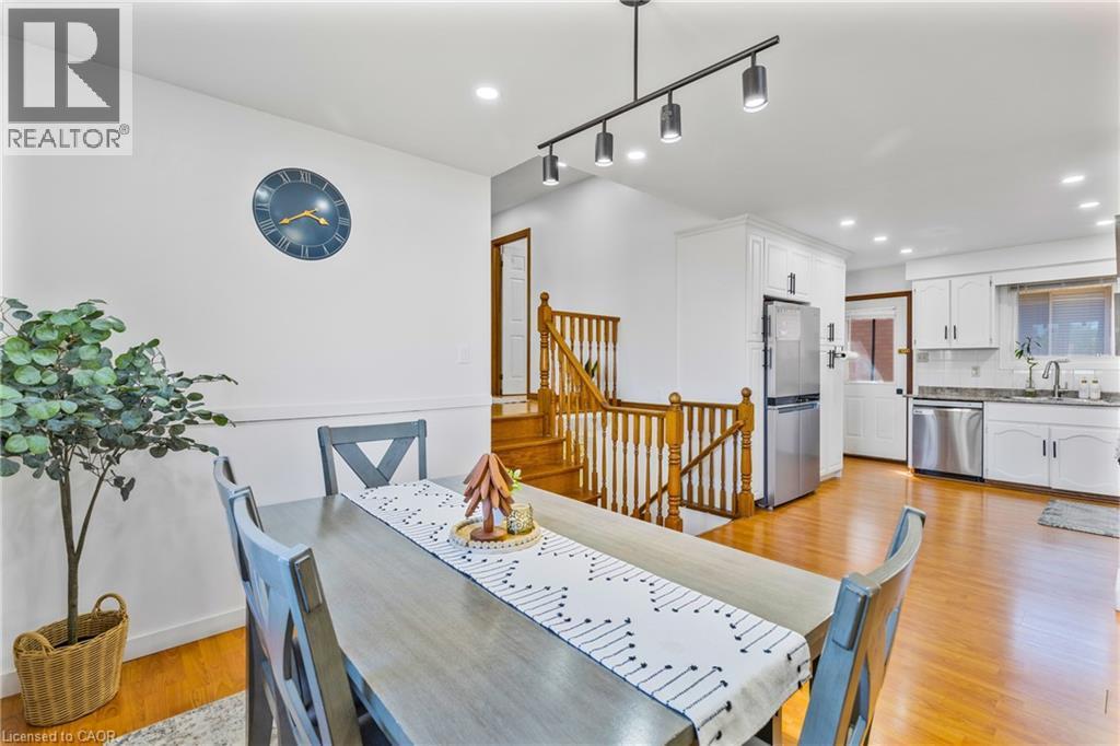 Open-concept dining area featuring wood-finish flooring, a contemporary track light fixture, and white wall finishes - 102 Juniper Drive, Hamilton, ON