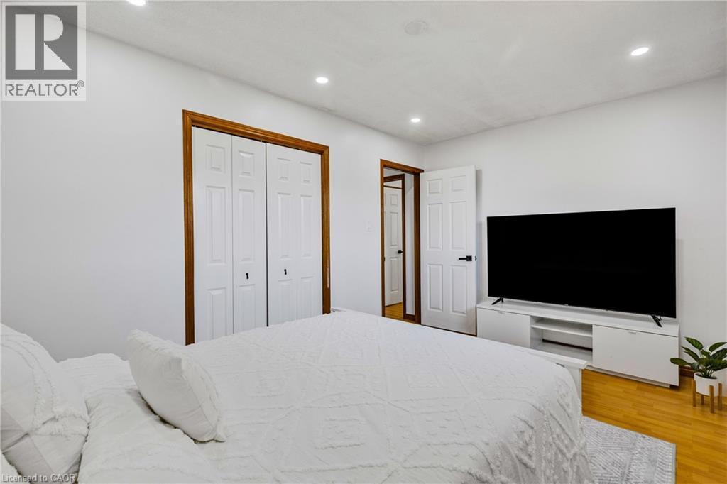 Spacious room featuring wood-finish flooring, recessed lighting, white panel doors with wood trim, and a built-in media console - 102 Juniper Drive, Hamilton, ON